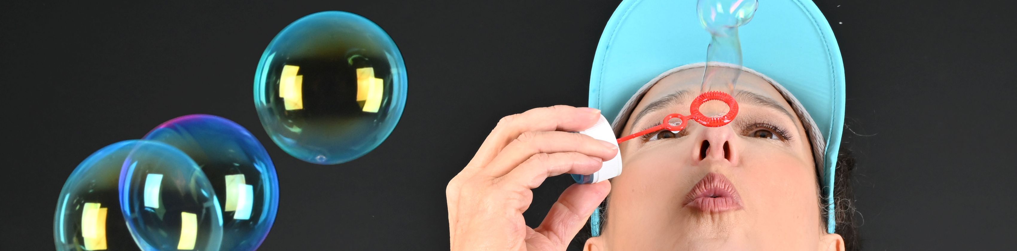 Stefanie Kerker mit türkisfarbener Schirmmütze. Sie macht Seifenblasen., © Stefanie Kerker Stefanie Kerker mit türkisfarbener Schirmmütze. Sie macht Seifenblasen., © Stefanie Kerker