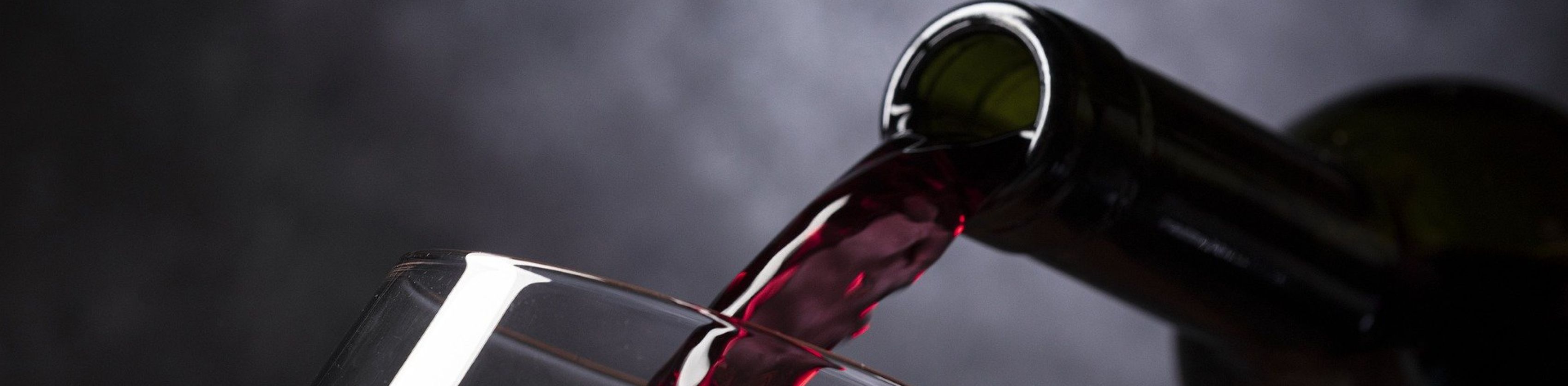 Rotwein wird in ein Glas eingeschenkt