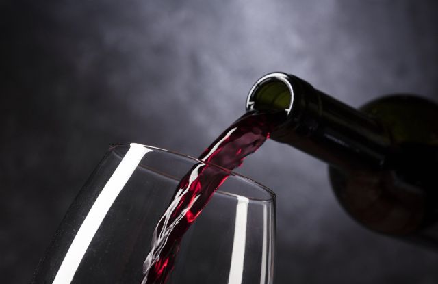 Rotwein wird in ein Glas eingeschenkt