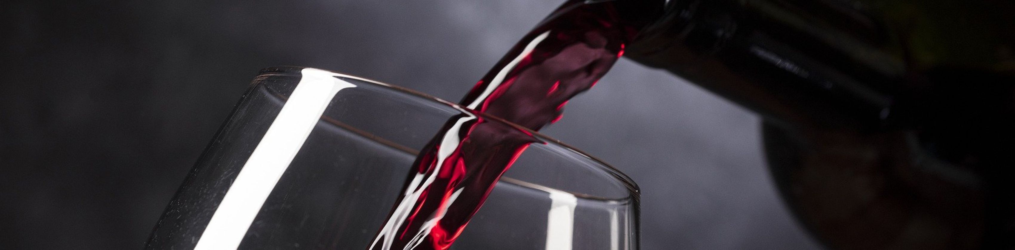 Rotwein wird in ein Glas eingeschenkt