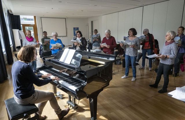 Eine Gruppe &auml;lterer Damen und Herren steht neben einem Piano und singt zu Musikbegleitung., &copy; keb Heilbronn e.V.